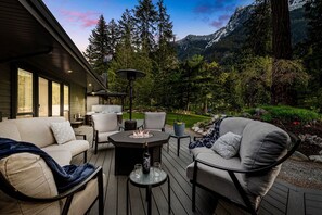 An outdoor deck with a fire pit, seating, and a view of a mountainous landscape.