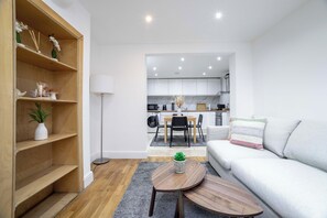 A modern living room with a sofa, a coffee table, and a wooden bookshelf. - 3 bedroom house in Notting Hill (London)