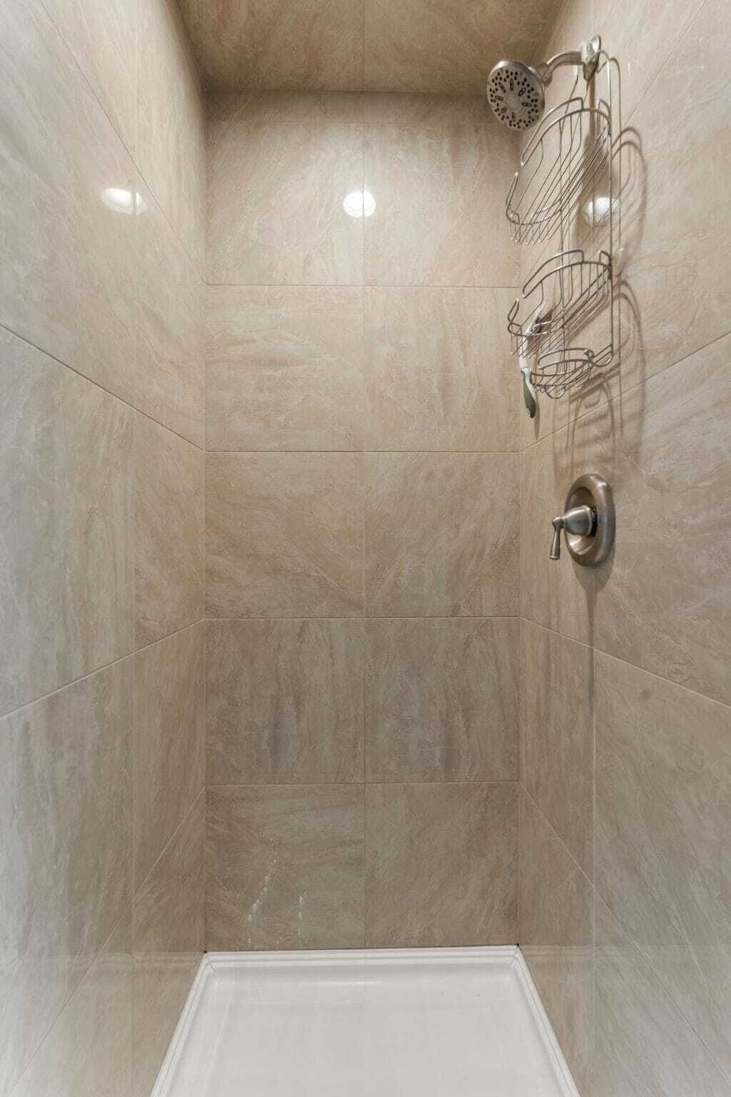 Une douche moderne dotée d’un pommeau de douche fixé au mur et d’un flexible de douche.