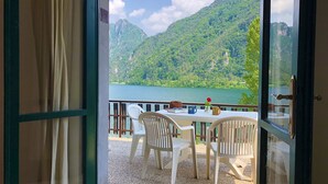A room with a table and chairs facing a scenic mountain view and lake. - Directly on the lake with terrace (Tre Capitelli)