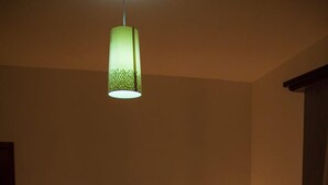 A bedroom with a curved headboard, a bed with a floral bedspread, and a green pendant light.