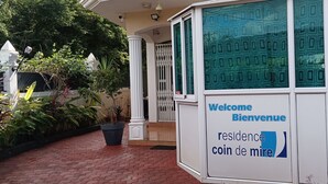 A building entrance with a welcome sign, a gated entrance, and potted plants.