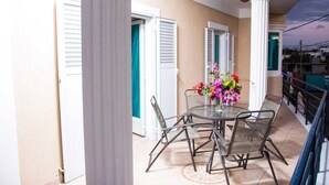 A balcony with a round table and chairs, a vase of flowers, and a view of the cityscape.