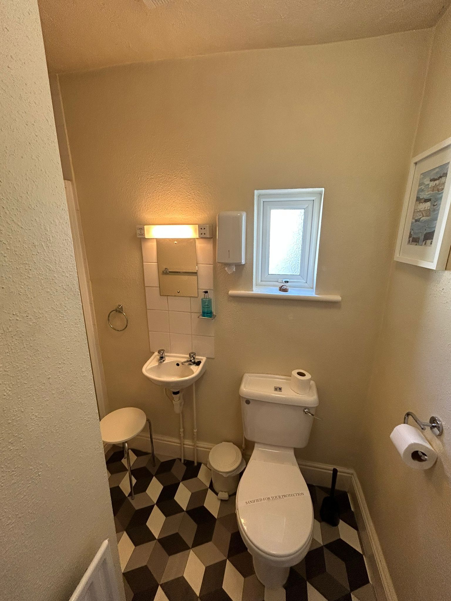 A small bathroom with a toilet, sink, and a window above the sink.
