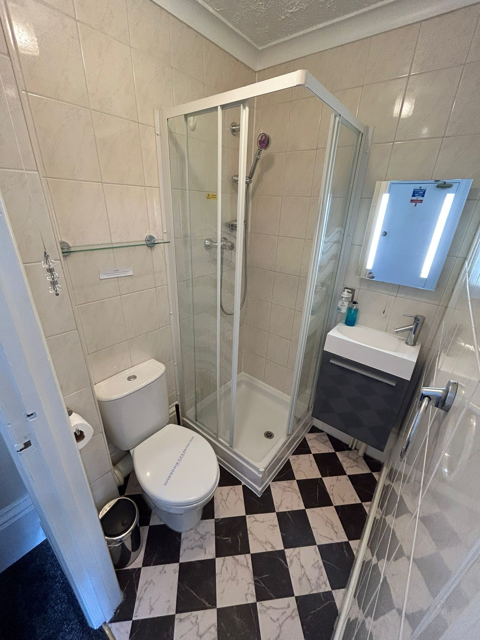 Een badkamer met een douchecabine van glas, een toilet en een wastafel.