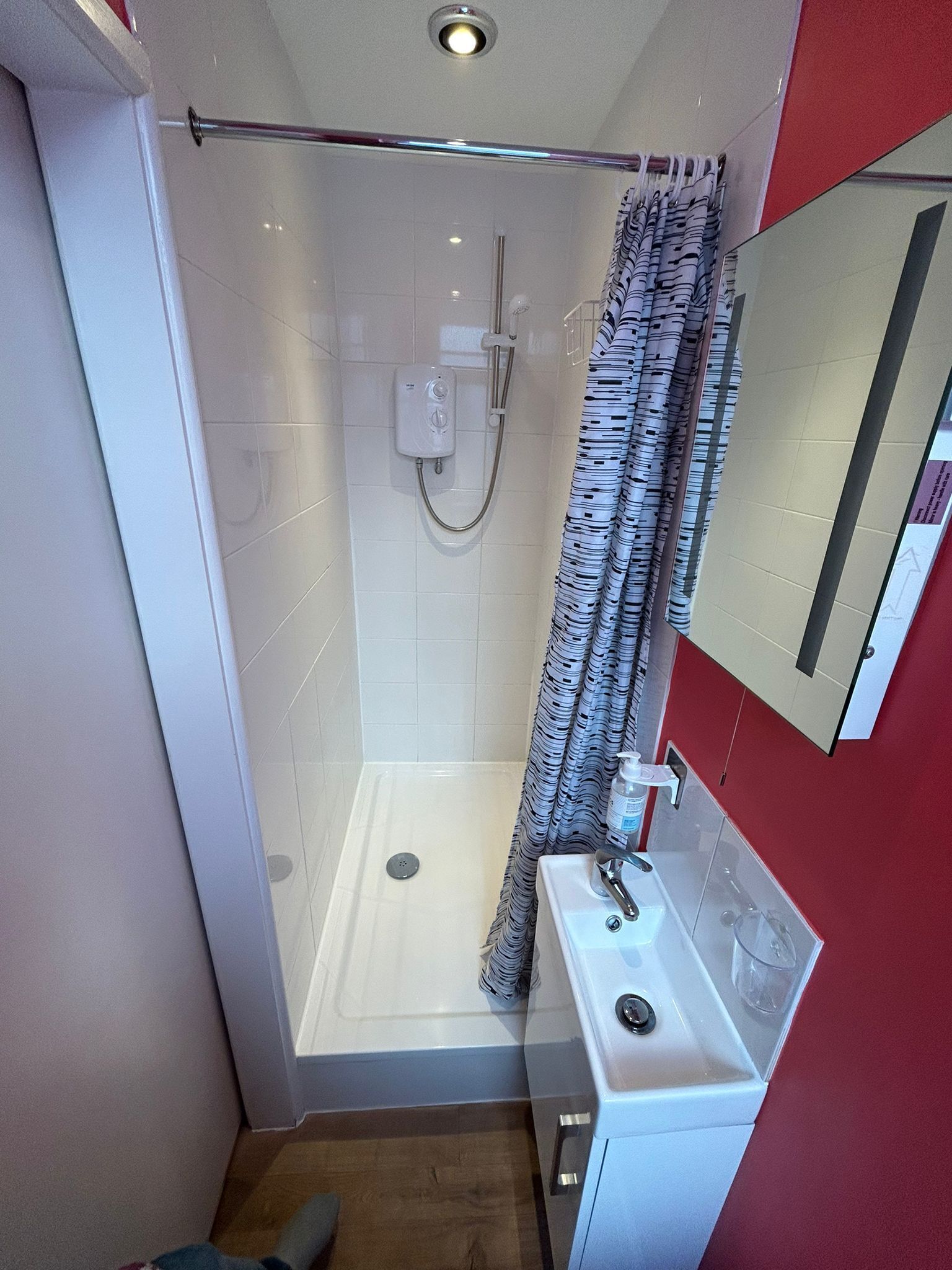 A modern bathroom with a glass shower enclosure, a white sink, and a mirror.