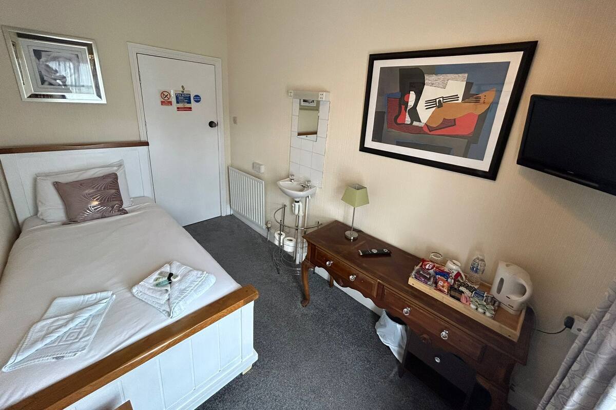 Une chambre d’hôtel comprenant un lit, une commode, un miroir, un tableau encadré et un téléviseur.