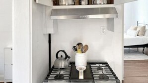 A modern kitchen with a white stove, a kettle, and a spice jar on the countertop. - Best neighborhood in SA! Near it all, food & fun!
 (San Antonio)