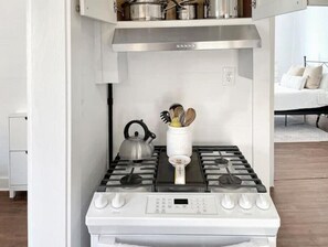 A modern kitchen with a white stove, a kettle, and a spice jar on the countertop. - Best neighborhood in SA! Near it all, food & fun!
 (San Antonio)