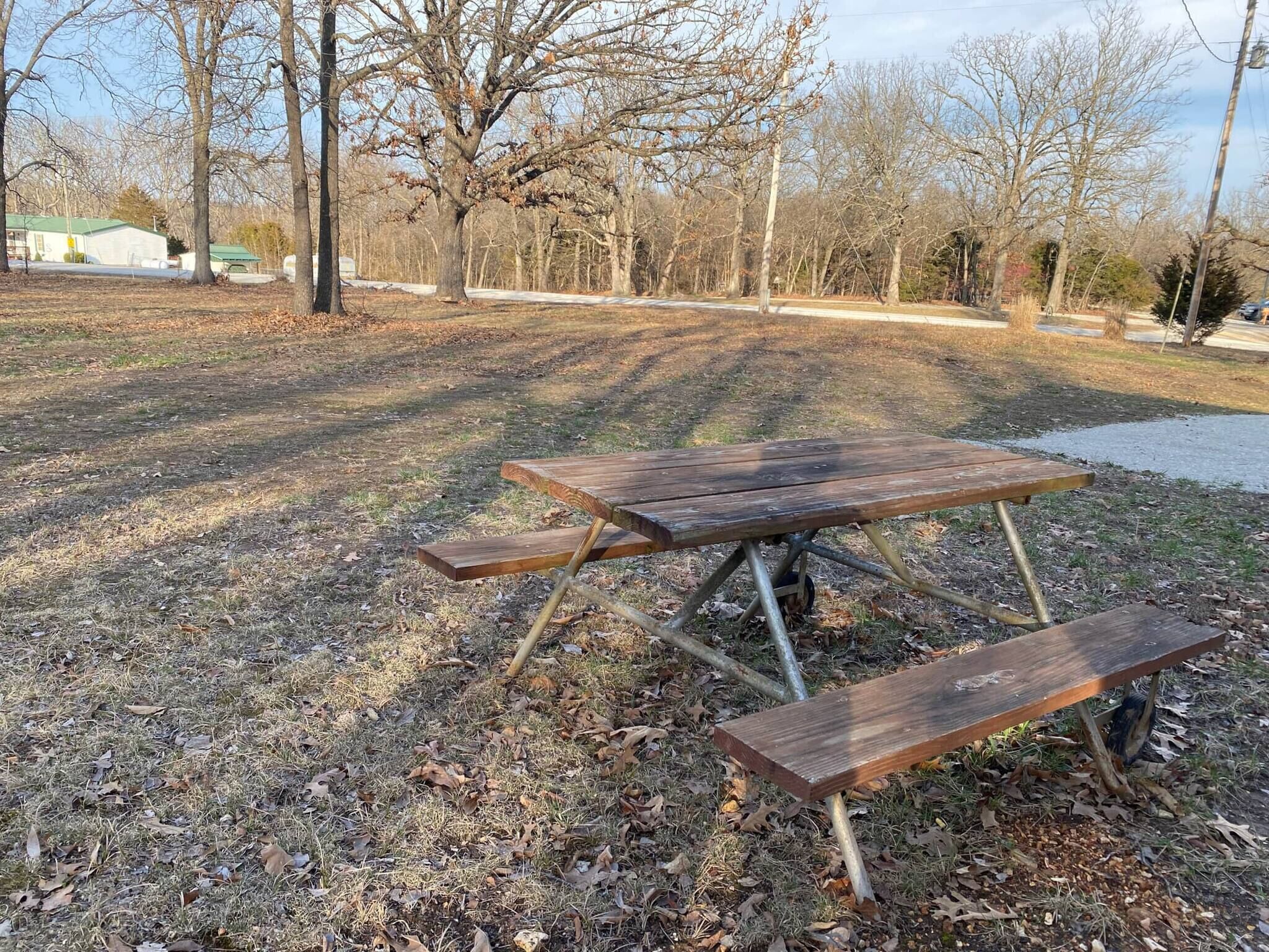 A picnic table in a park with bare trees and a building in the background.
