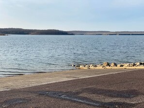 Una spiaggia con un litorale roccioso e un ponte in lontananza.