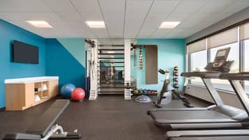 Uma academia com esteiras, bolas de exercício e suporte para pesos.
