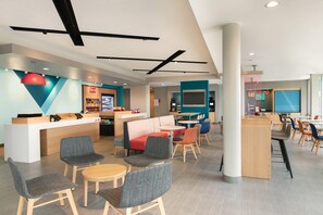 A modern hotel lobby with seating areas, a reception desk, and a visible restaurant counter. - Avid Hotel Traverse City By IHG (Traverse City)