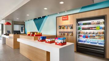 Uma área de recepção moderna com balcão, vitrine refrigerada e um letreiro na parede com a inscrição 'Market'.