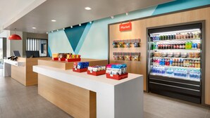 A modern reception area with a counter, a refrigerated display case, and a wall-mounted sign labeled "Market". - Avid Hotel Traverse City By IHG (Traverse City)
