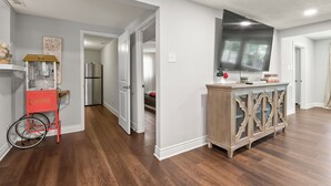 A modern kitchen with wooden flooring, a popcorn cart, and a large flat-screen TV mounted above the counter.