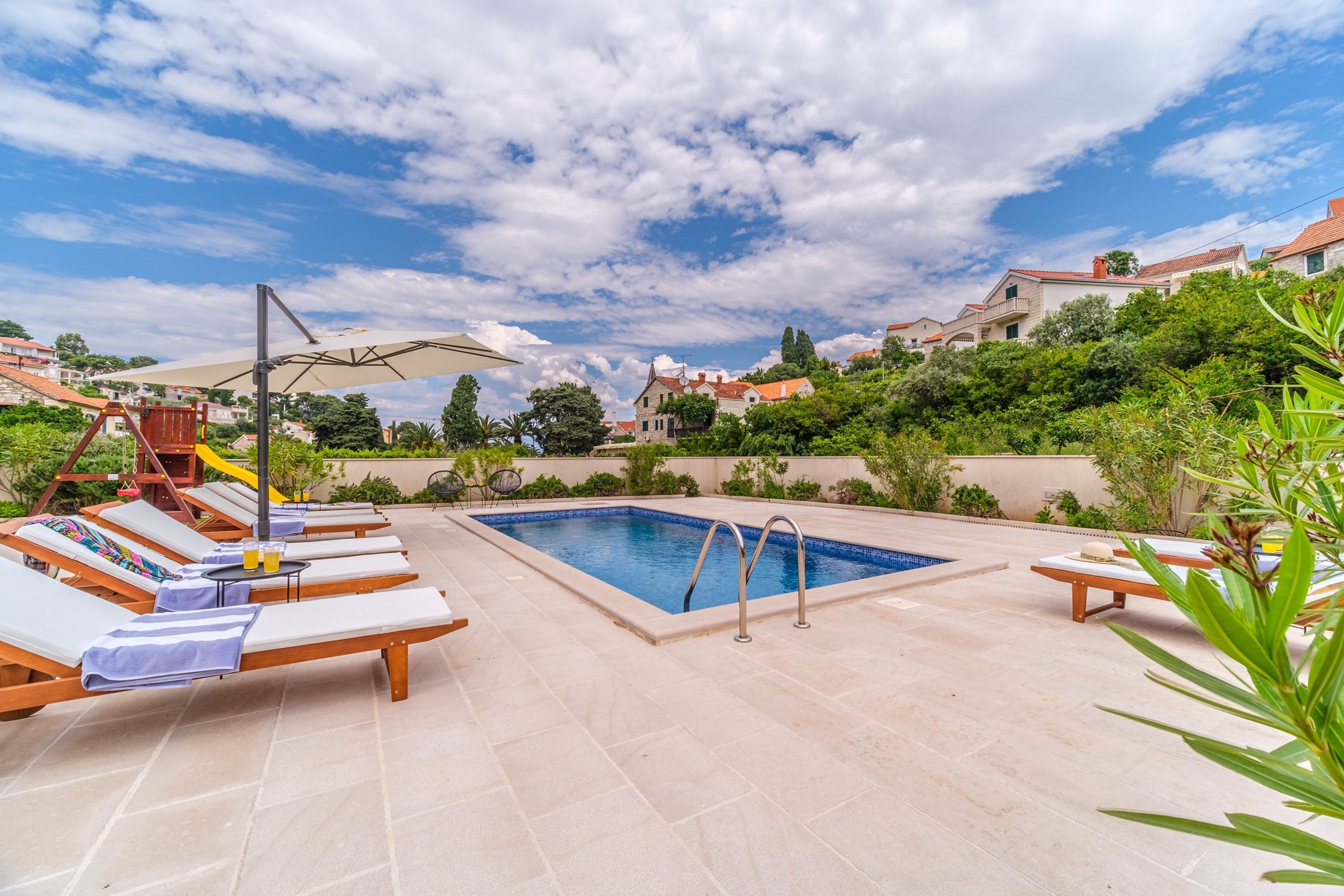 A pool area with lounge chairs, a diving board, and a clear blue sky.