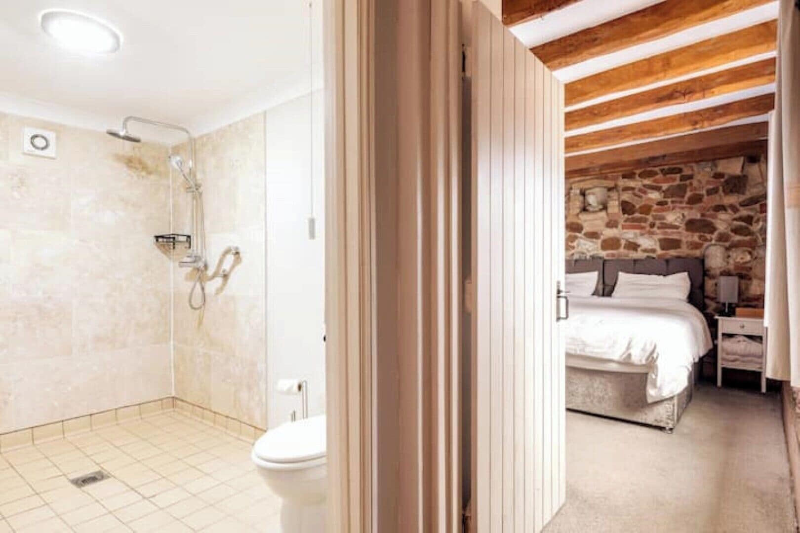 Ein Badezimmer mit Dusche und WC, sowie ein Schlafzimmer mit Bett und Nachttisch.
