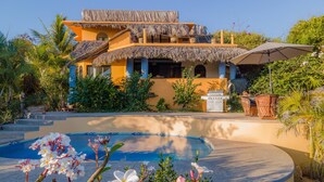 Un resort con piscina, zona de barbacoa y vegetación tropical.