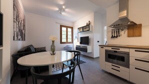 A modern kitchen with a dining area, a large window, and a mounted TV. - Loft Gran Canaria (Arucas)