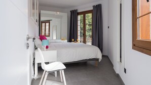A bedroom with a bed, a desk, a chair, a window with curtains, and a view of the outdoors. - Loft Gran Canaria (Arucas)