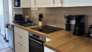 Cozinha moderna com armários brancos, bancada de madeira, forno embutido, lava-louças, micro-ondas e cafeteira.