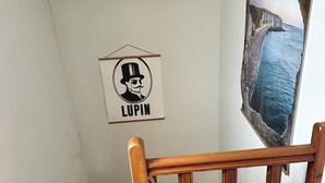 Uma escadaria de madeira com corrimão, um cartaz emoldurado com a palavra 