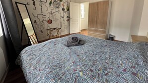 Quarto com colcha estampada, um espelho e parede com design mecânico.