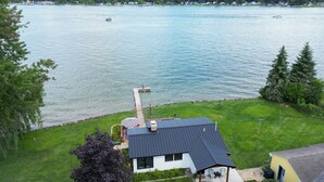 Une maison avec une jetée qui s’avance sur un lac, entourée de verdure et offrant une vue dégagée sur l’eau.
