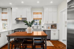 Enjoy meals in this kitchen with a dining table for four, stainless steel range hood, and large window with an outside view.