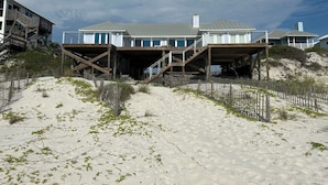Una casa frente a la playa con una terraza de madera y varios niveles.