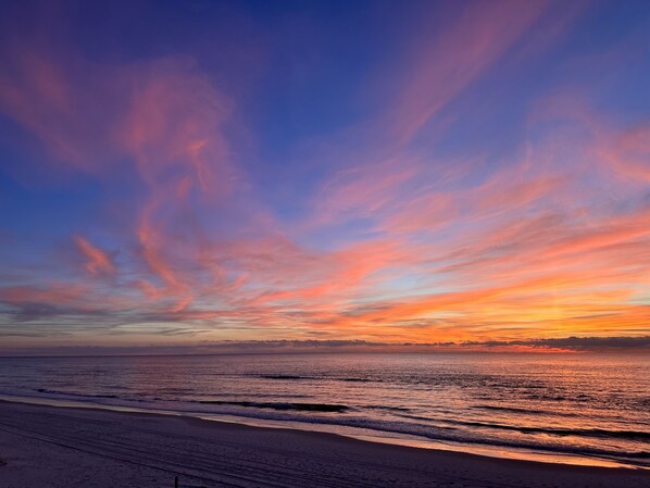 Una playa con un atardecer y olas del océano.