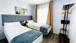 A hotel room with two beds, a headboard, a bedside table with a lamp, a wardrobe, and a mirror on the wall. - Casa SoHo y Alex, Apartment 3B- 2 bedrooms (Estepona)