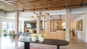 A modern lobby with a central table, potted plants, a patterned rug, and a wooden ceiling. - Bridge Creek Inn (Clayton)