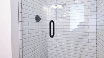 A glass-enclosed shower with white subway tiles and a pebble-patterned floor.