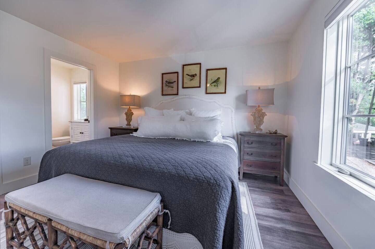 Een slaapkamer met een groot bed, nachtkastjes, een bankje en ingelijste foto's aan de muur.