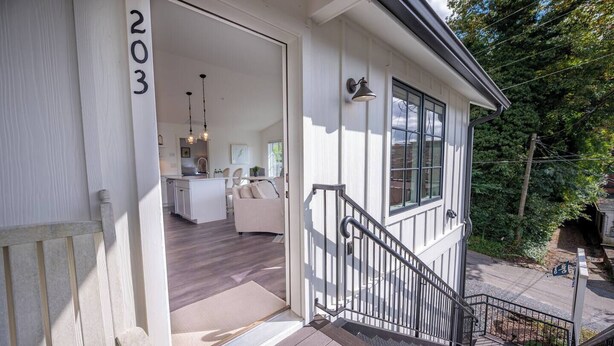 A two-story house with a visible number '203' on the exterior wall, a staircase leading to the upper floor, and a small porch area. - Bridge Creek Inn (Clayton)