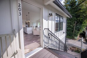 Une maison à deux étages, avec le numéro « 203 » bien visible sur le mur extérieur, un escalier menant à l’étage supérieur et un petit porche.