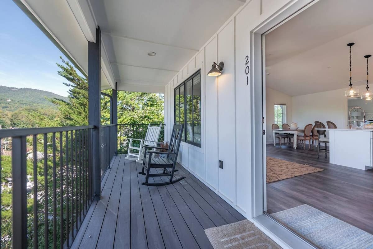 A wooden deck with two rocking chairs, a dining area with a table and chairs, and a kitchen with a sink and counter.