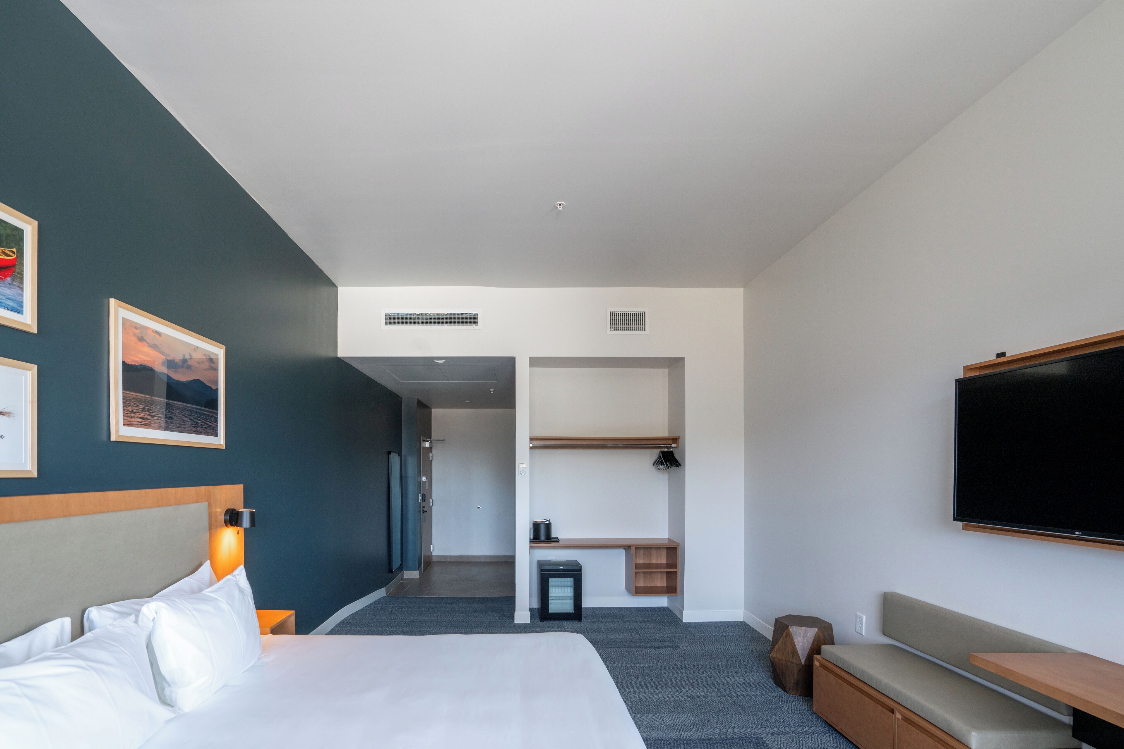 Una habitación de hotel moderna con cama, zona de estar, televisor y un pequeño escritorio.