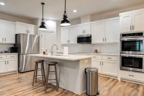 Enjoy cooking in this fully equipped kitchen with a refrigerator, microwave, and double oven, complemented by a central island with stools.