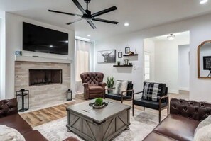 Relax in this stylish living room with a large flat-screen TV, fireplace, and comfortable seating for two.