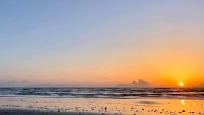 A beach scene with a sunset over the ocean.