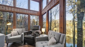 Ein gemütliches Blockhaus-Interieur mit großen Fenstern, Holzbalken und einem Kamin.