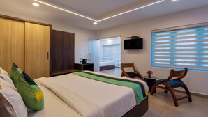 A modern hotel room with a bed, a desk, a chair, and a TV. - Treebo Vsaffron Regency, Punnamada Lake (Ambalapuzha)
