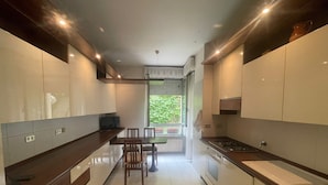 Una cocina moderna con armarios blancos, encimera de madera y una zona de comedor con sillas.