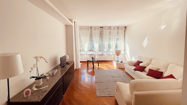 Una sala de estar moderna con un sofá, una mesa de centro, un televisor y una lámpara.