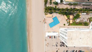 Vista aerea di un hotel fronte spiaggia con piscina, area spiaggia e parcheggio.