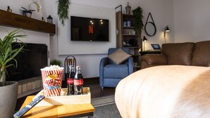 Olohuone, jossa on televisio, sohva, sohvapöytä, popcornia ja Coca-Cola-pulloja.