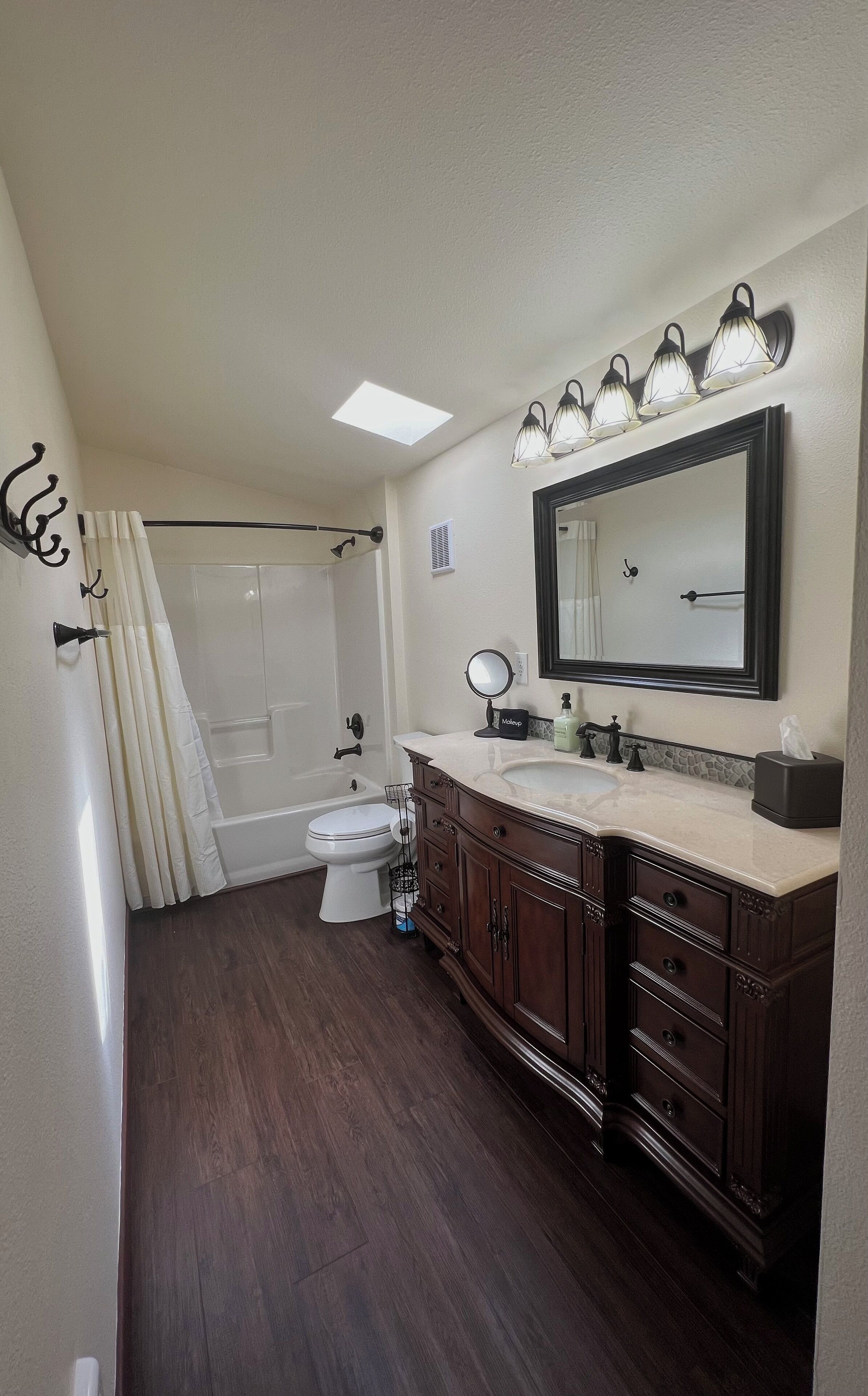 A bathroom with a bathtub, toilet, vanity with a mirror, and a shower curtain.